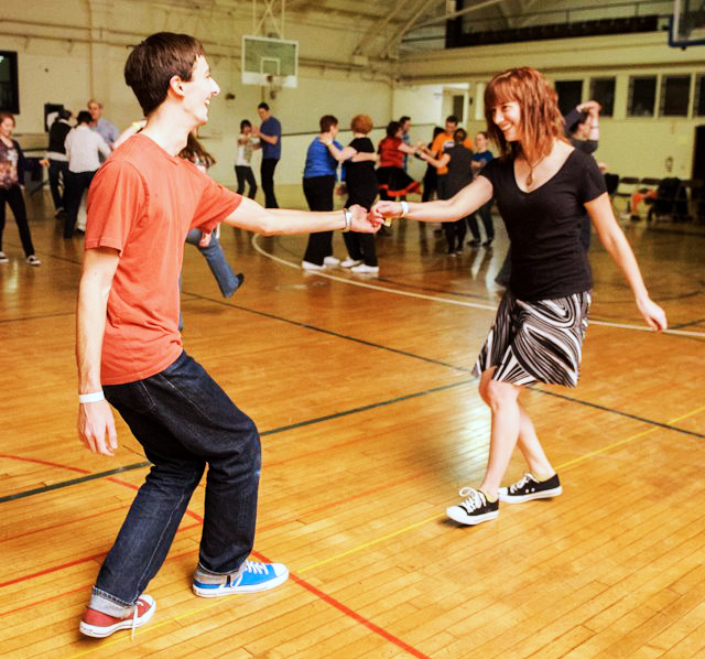 Sarah, a strength coach, dancing lindy hop in 2012 in a black t-shirt and black and white skirt. 