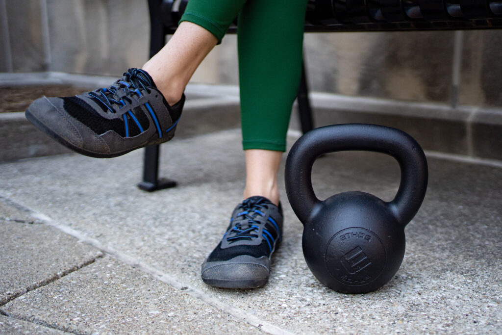 a kettlebell sits on the ground by the feet of someone with their legs crossed