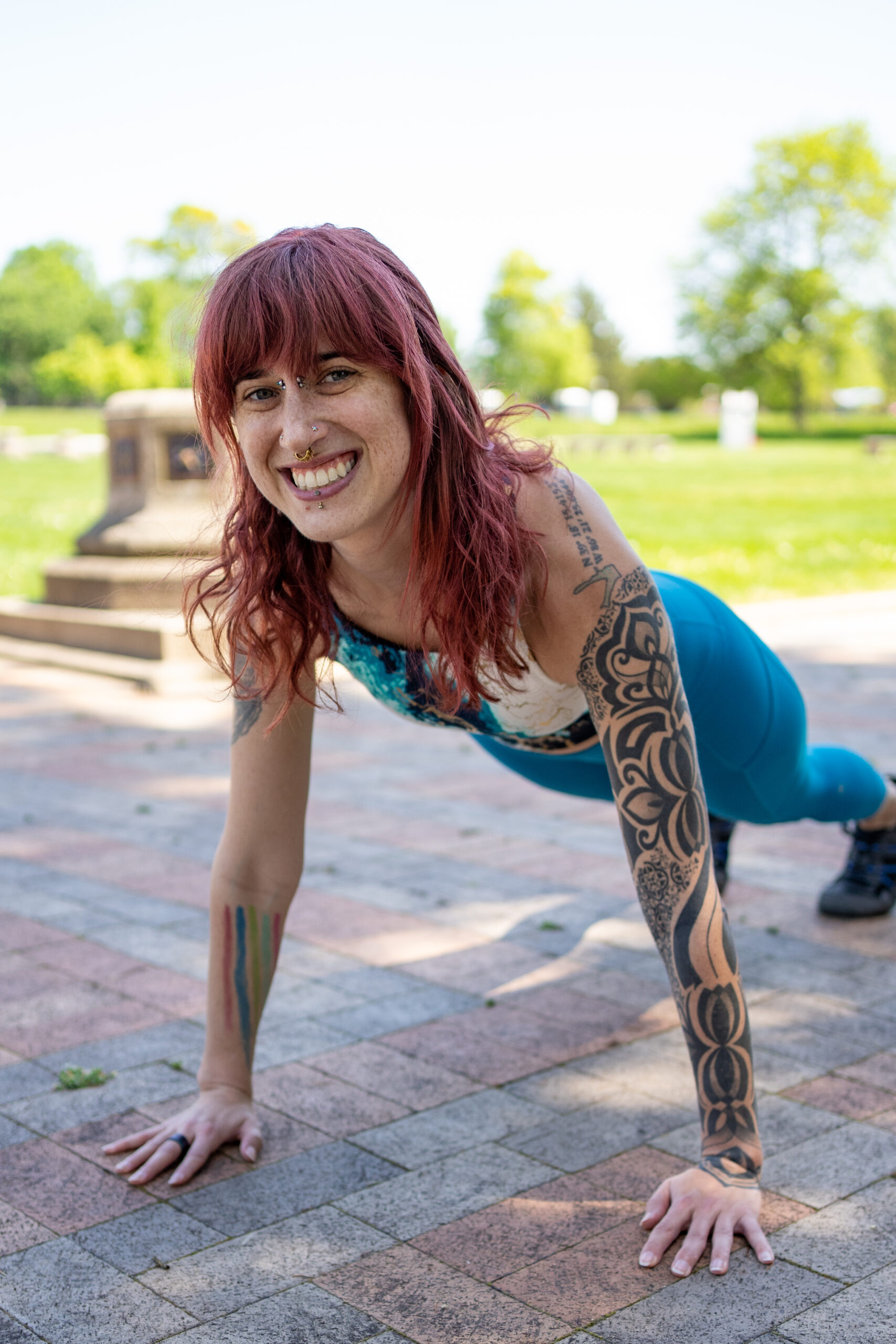 Woman wearing blue workout gear doing a plank outside.