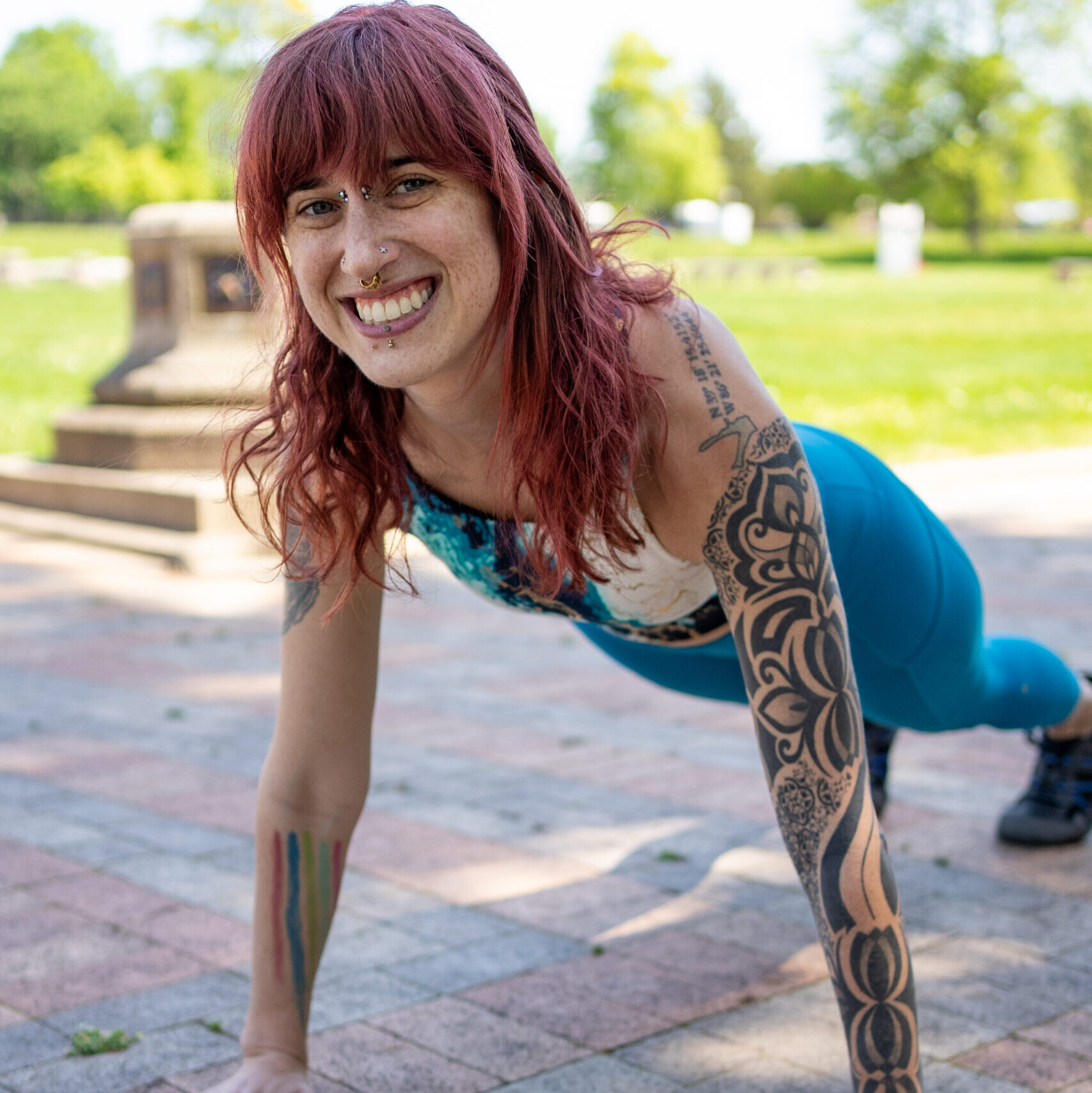 Woman wearing blue workout gear doing a plank outside.